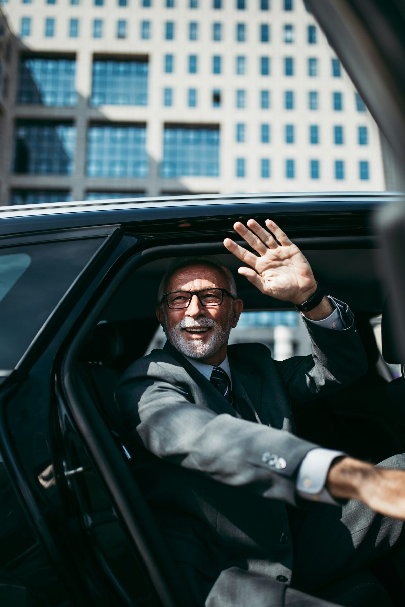 Senior business traveler waving as exiting the vehicle